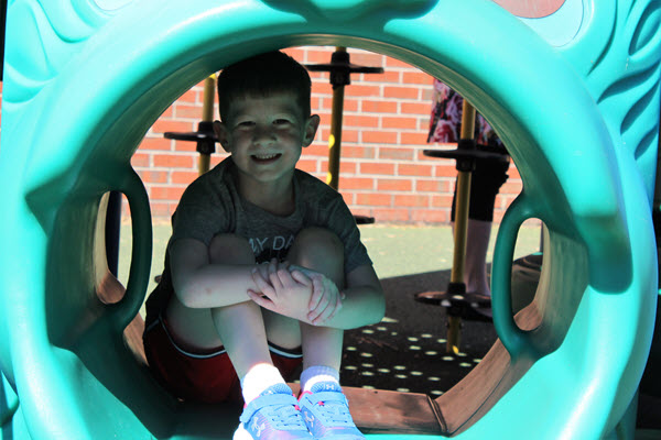 child sitting inside playground tunnel